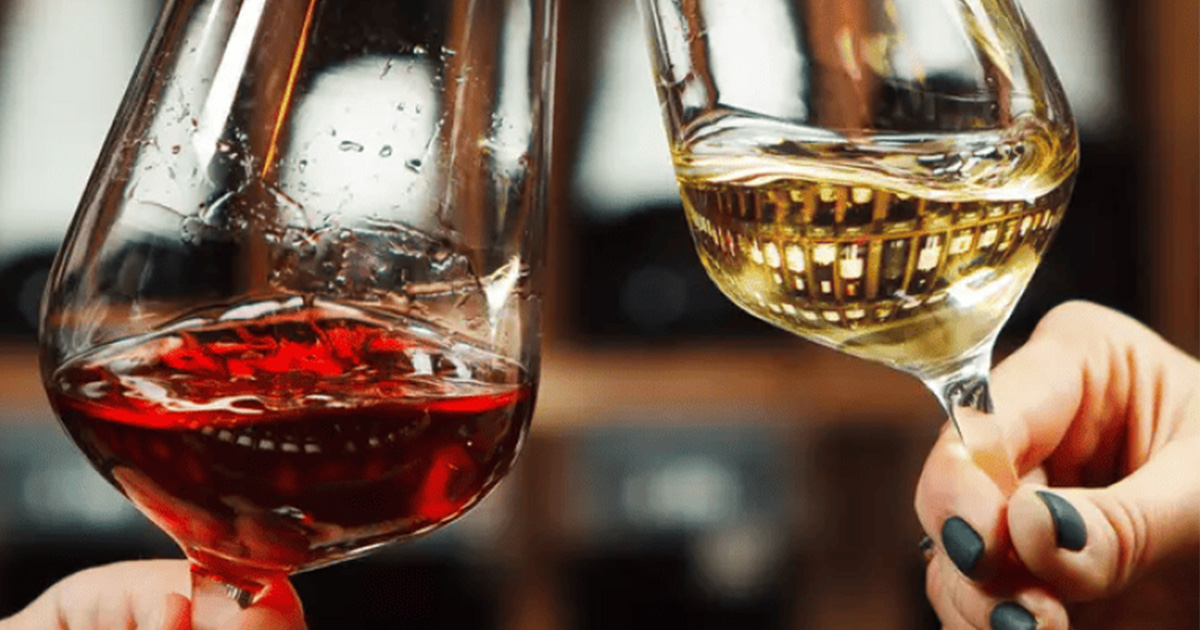Deux verres de vin, rouge et blanc, portés pour trinquer.